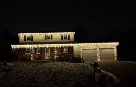 Warm-white icicle Christmas lights along the roofline of a two-story home, installed by Lighting Squad